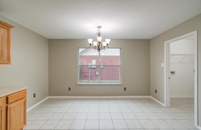 unfurnished dining area featuring light tile patterned floors, a textured ceiling, and an inviting chandelier