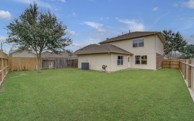 back of house with central AC unit and a lawn