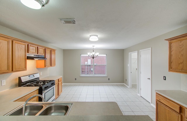 kitchen featuring sink, hanging light fixtures, a chandelier, range with gas stovetop, and light tile patterned flooring