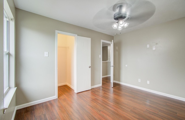 unfurnished bedroom with ceiling fan, dark hardwood / wood-style floors, a spacious closet, and a closet