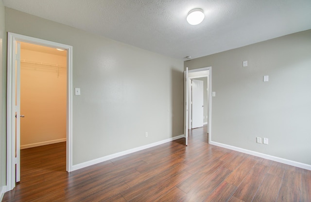 empty room with a textured ceiling and dark hardwood / wood-style floors