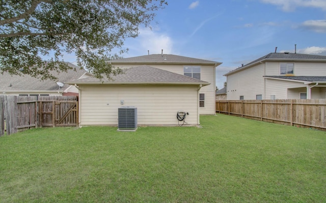 back of house with central air condition unit and a lawn