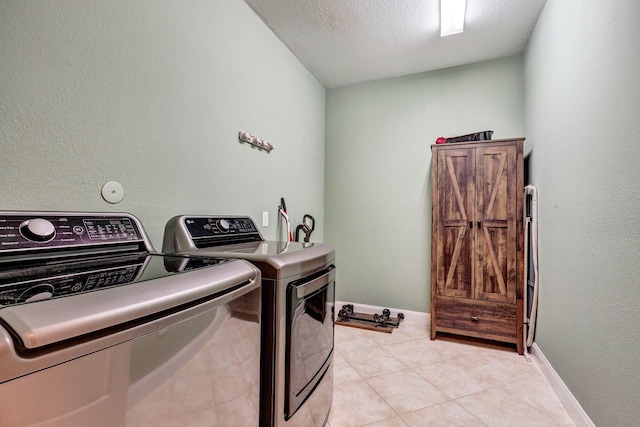 clothes washing area with laundry area, baseboards, a textured ceiling, and washing machine and clothes dryer