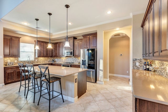 kitchen featuring pendant lighting, crown molding, a breakfast bar, stainless steel appliances, and a center island