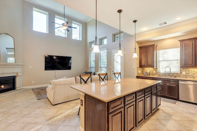 kitchen featuring sink, a breakfast bar, a kitchen island, decorative light fixtures, and stainless steel dishwasher