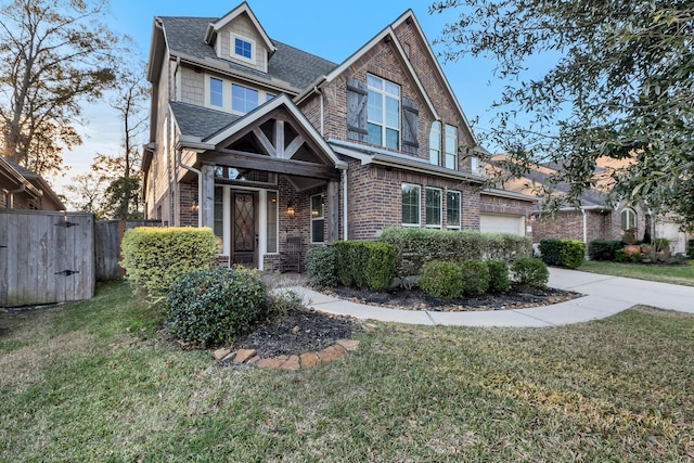 view of front facade featuring brick siding, roof with shingles, a front yard, a garage, and driveway