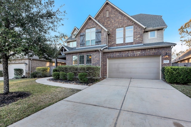 view of front of house with concrete driveway, an attached garage, a front yard, brick siding, and roof with shingles