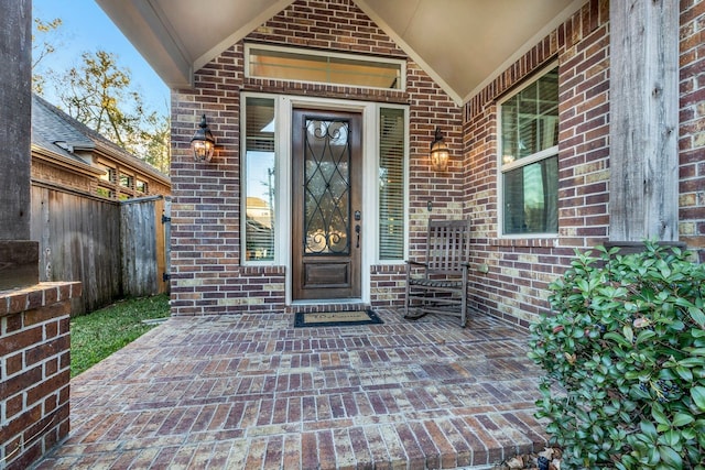 property entrance featuring brick siding and fence