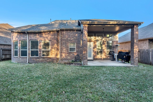 rear view of property with a patio area, a yard, a fenced backyard, and brick siding