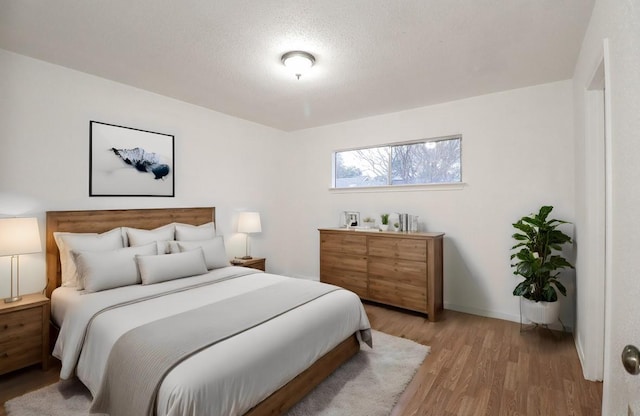 bedroom featuring a textured ceiling and light hardwood / wood-style flooring