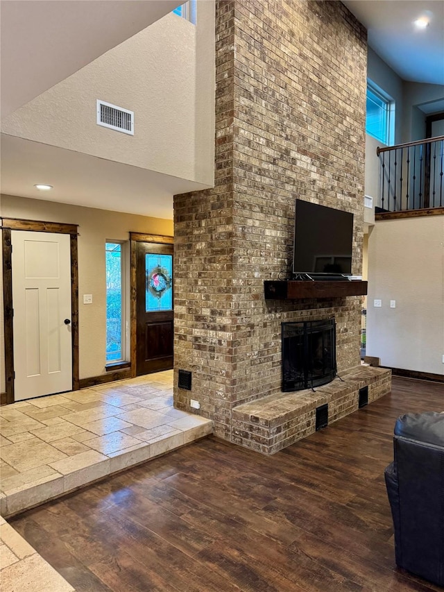 unfurnished living room with wood-type flooring and a brick fireplace