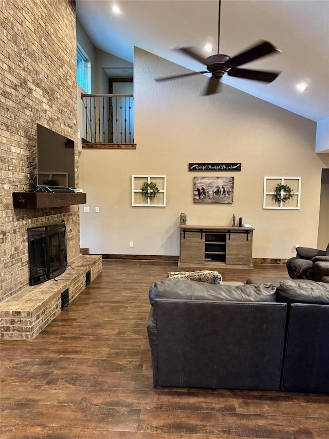 living room featuring ceiling fan, a fireplace, high vaulted ceiling, and dark wood-type flooring