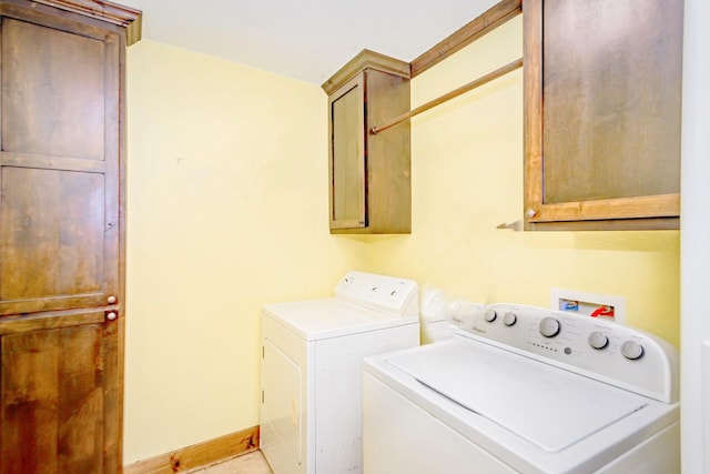 clothes washing area featuring cabinets and washing machine and clothes dryer