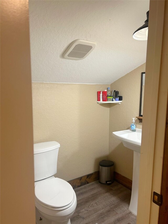 bathroom featuring hardwood / wood-style flooring, toilet, and lofted ceiling