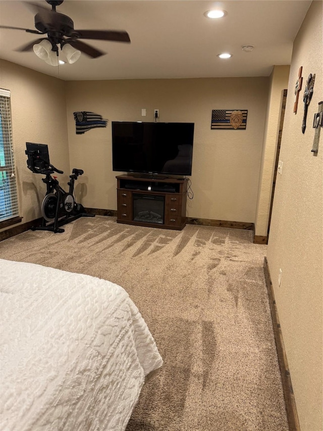 carpeted bedroom featuring a fireplace and ceiling fan