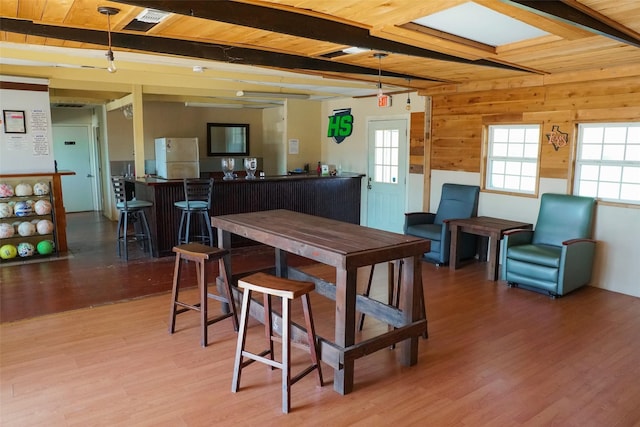 dining room with beam ceiling, wood ceiling, indoor bar, and hardwood / wood-style floors