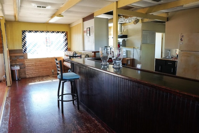 kitchen featuring beam ceiling, sink, fridge, and a breakfast bar area