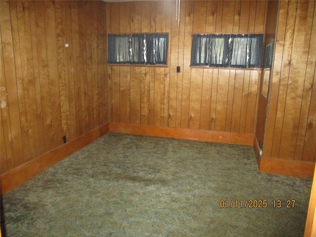 carpeted empty room featuring wooden walls