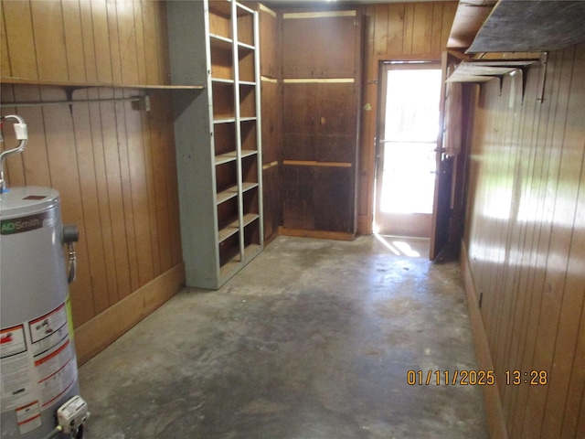 interior space with wood walls, concrete flooring, and water heater