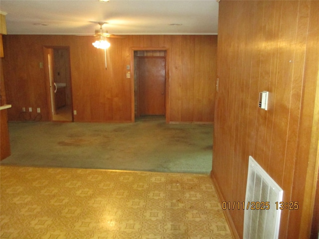 unfurnished room featuring ceiling fan and wood walls