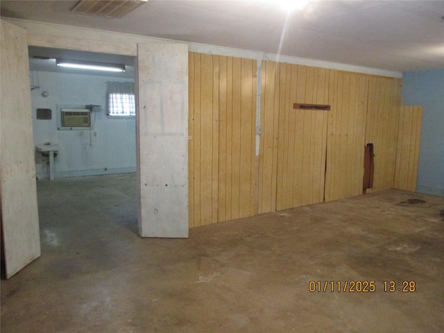 basement with a wall mounted air conditioner and wood walls