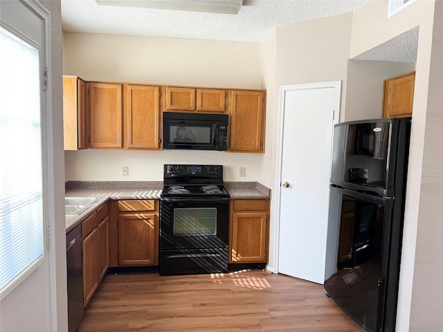 kitchen featuring black appliances, light hardwood / wood-style floors, and a textured ceiling