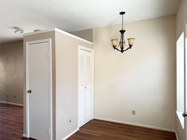 interior space featuring a textured ceiling, dark hardwood / wood-style floors, and a notable chandelier