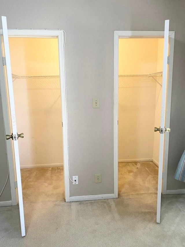 unfurnished bedroom featuring a walk in closet, a closet, and light colored carpet