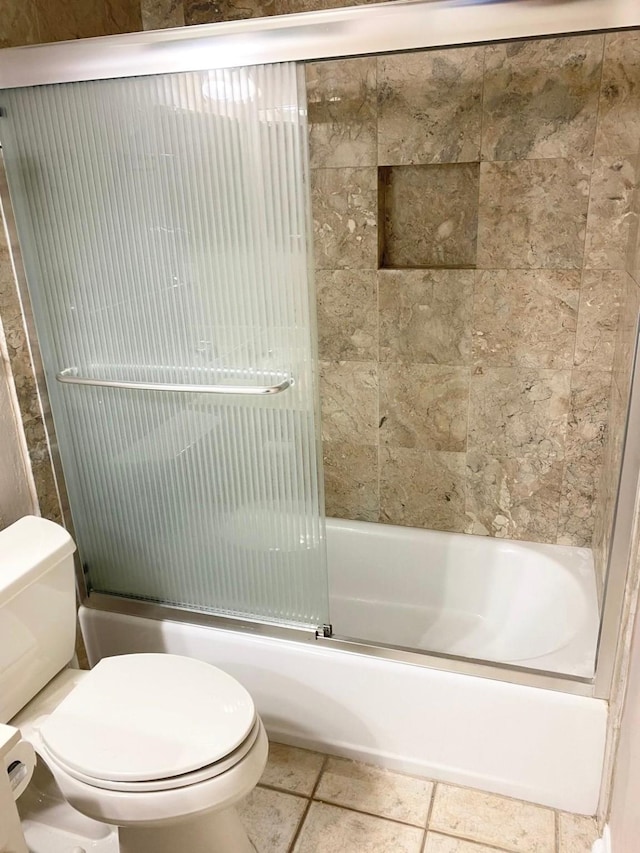 bathroom with tile patterned floors, enclosed tub / shower combo, and toilet