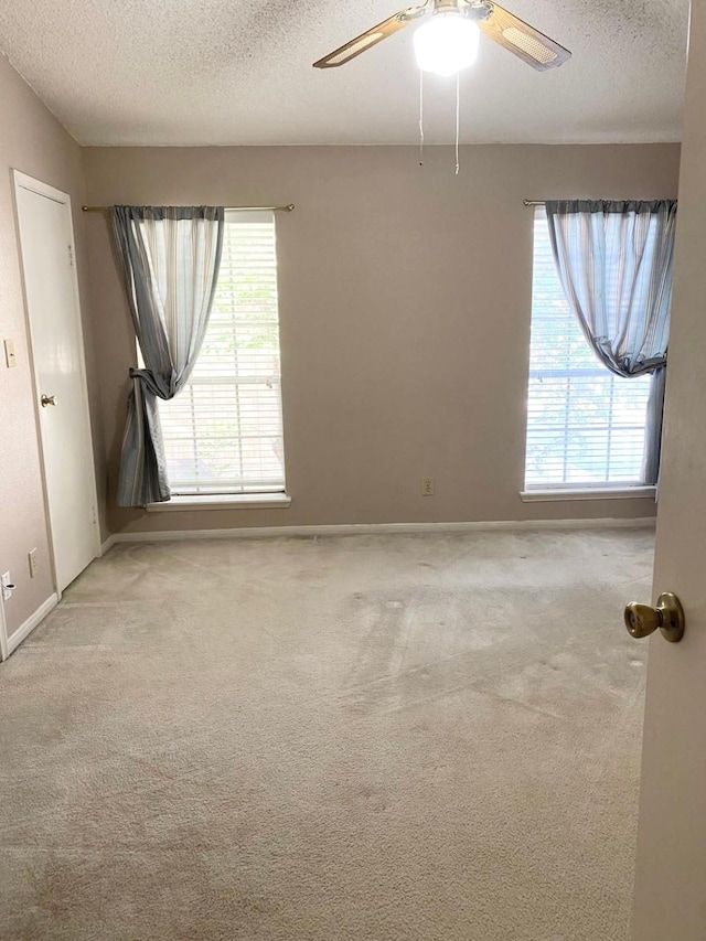 unfurnished room with ceiling fan, light colored carpet, and a textured ceiling