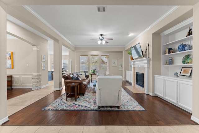 living room with crown molding, ceiling fan, light hardwood / wood-style flooring, and ornate columns