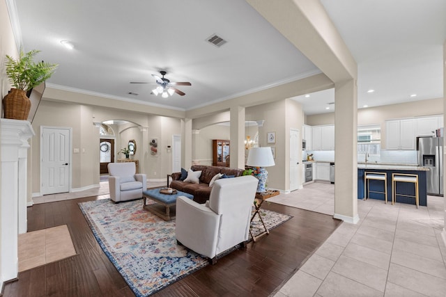 living room featuring sink, crown molding, light hardwood / wood-style floors, and ceiling fan