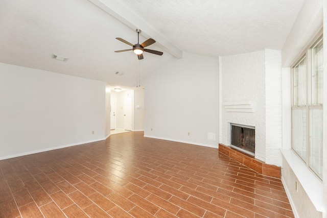 unfurnished living room with a textured ceiling, lofted ceiling with beams, a brick fireplace, and ceiling fan