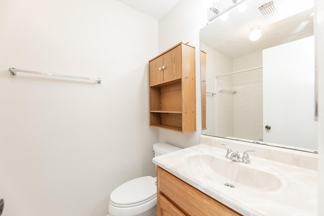 bathroom with vanity, toilet, and a shower