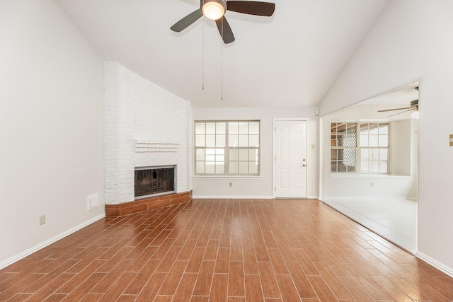 unfurnished living room with ceiling fan, a fireplace, a wealth of natural light, and vaulted ceiling