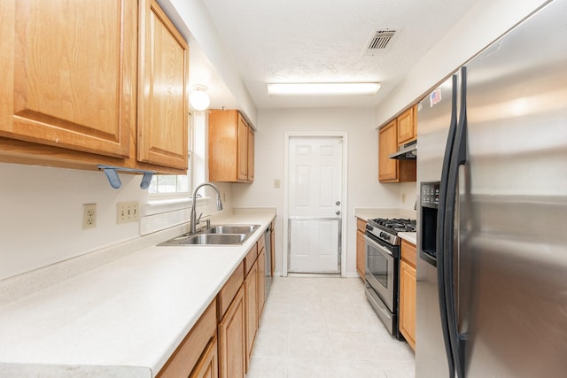 kitchen featuring a textured ceiling, stainless steel appliances, and sink