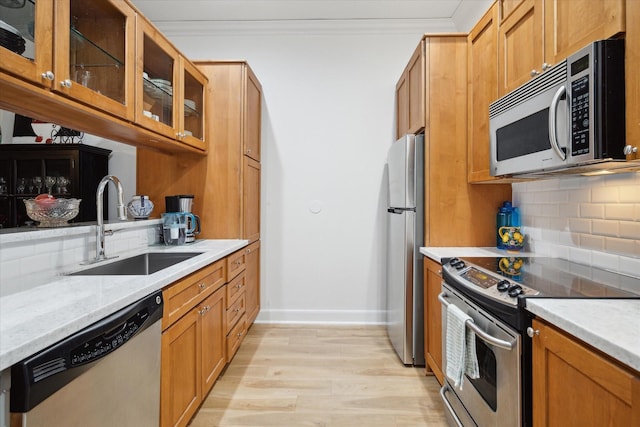 kitchen featuring decorative backsplash, light stone counters, stainless steel appliances, crown molding, and sink