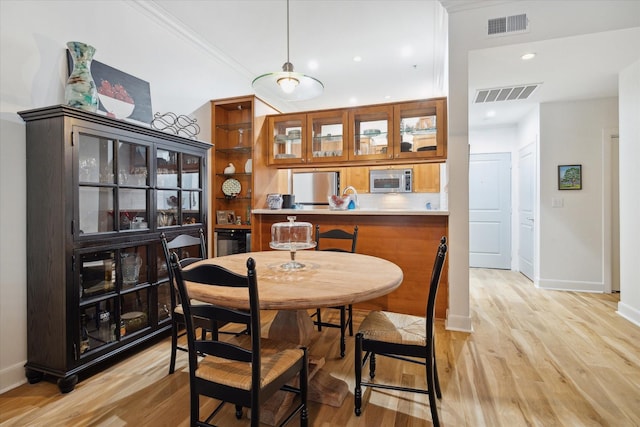 dining space with crown molding and light hardwood / wood-style flooring