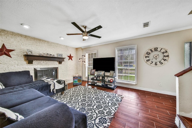 living area featuring a textured ceiling, a stone fireplace, visible vents, baseboards, and wood tiled floor