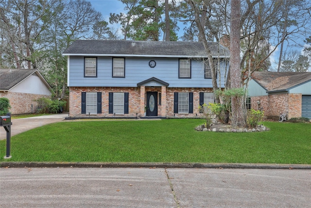 colonial-style house featuring a front yard, a chimney, and brick siding