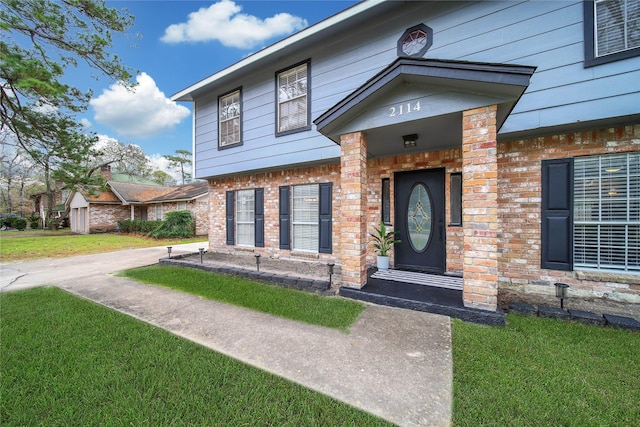 doorway to property featuring brick siding and a yard