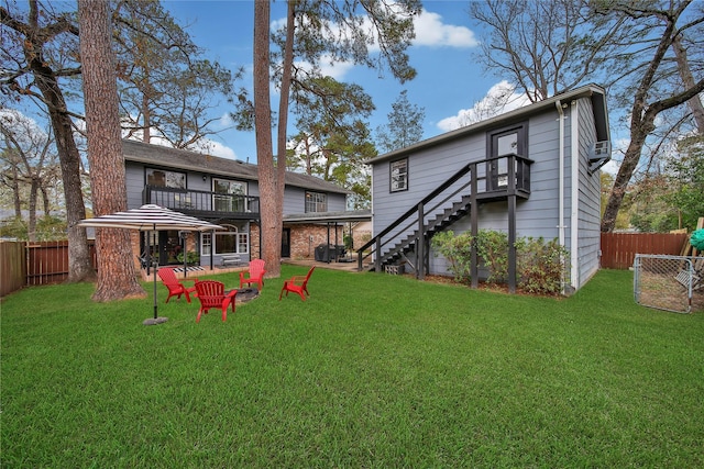 rear view of house featuring a yard, stairway, and fence