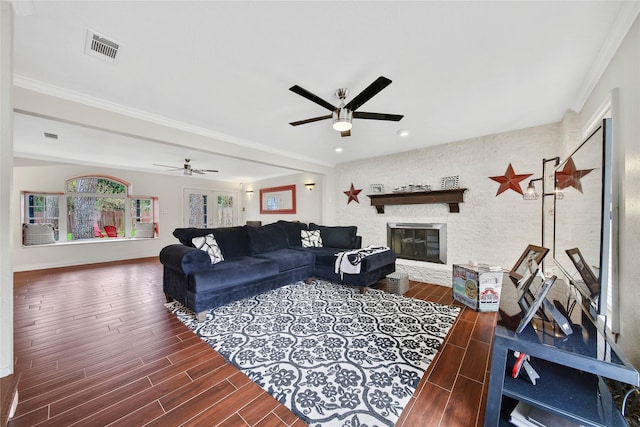 living room with a stone fireplace, ornamental molding, and ceiling fan