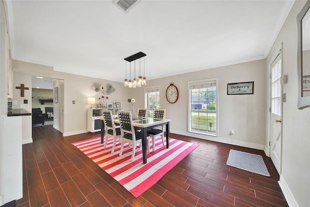 dining area with ornamental molding, wood tiled floor, visible vents, and a notable chandelier