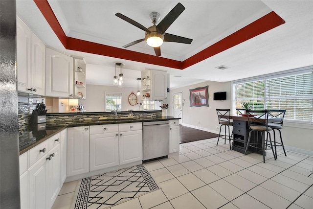 kitchen with dishwasher, dark countertops, a raised ceiling, and white cabinetry