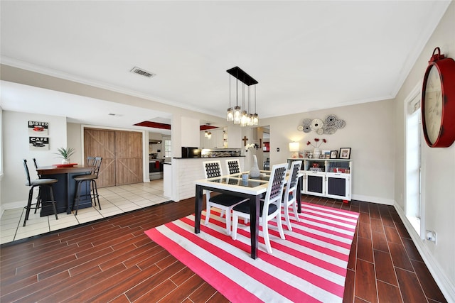 dining area with baseboards, visible vents, crown molding, wood finish floors, and a notable chandelier