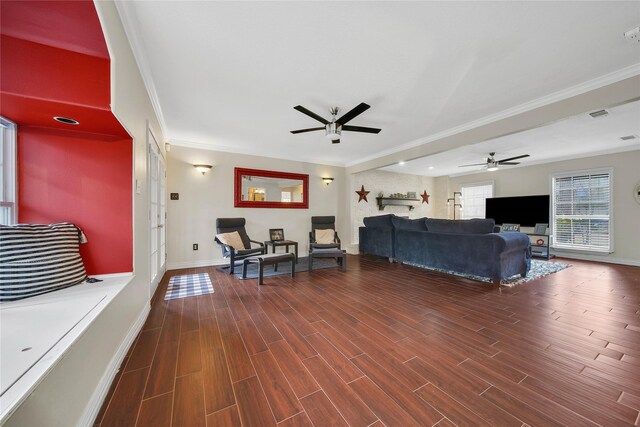 living area with dark wood-type flooring, ornamental molding, baseboards, and a ceiling fan