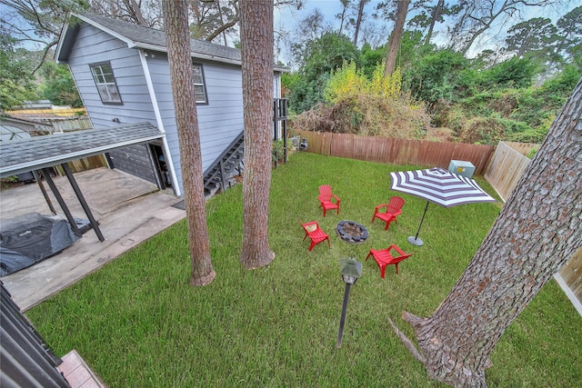 view of yard featuring a patio, an outdoor fire pit, an attached garage, and a fenced backyard