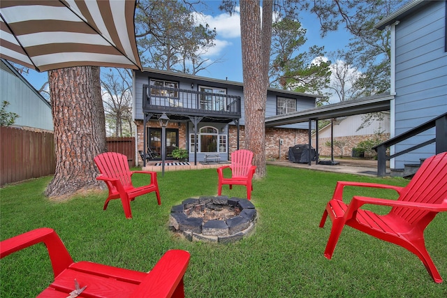 view of yard featuring a fire pit, a patio, fence, and a balcony