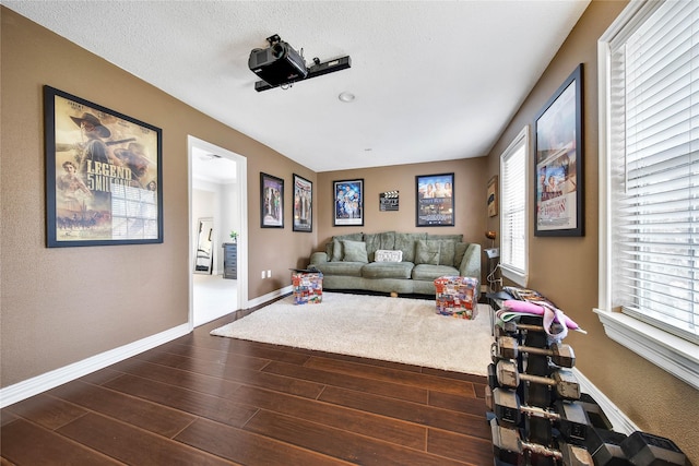 living room with dark wood-style floors, baseboards, and a textured ceiling